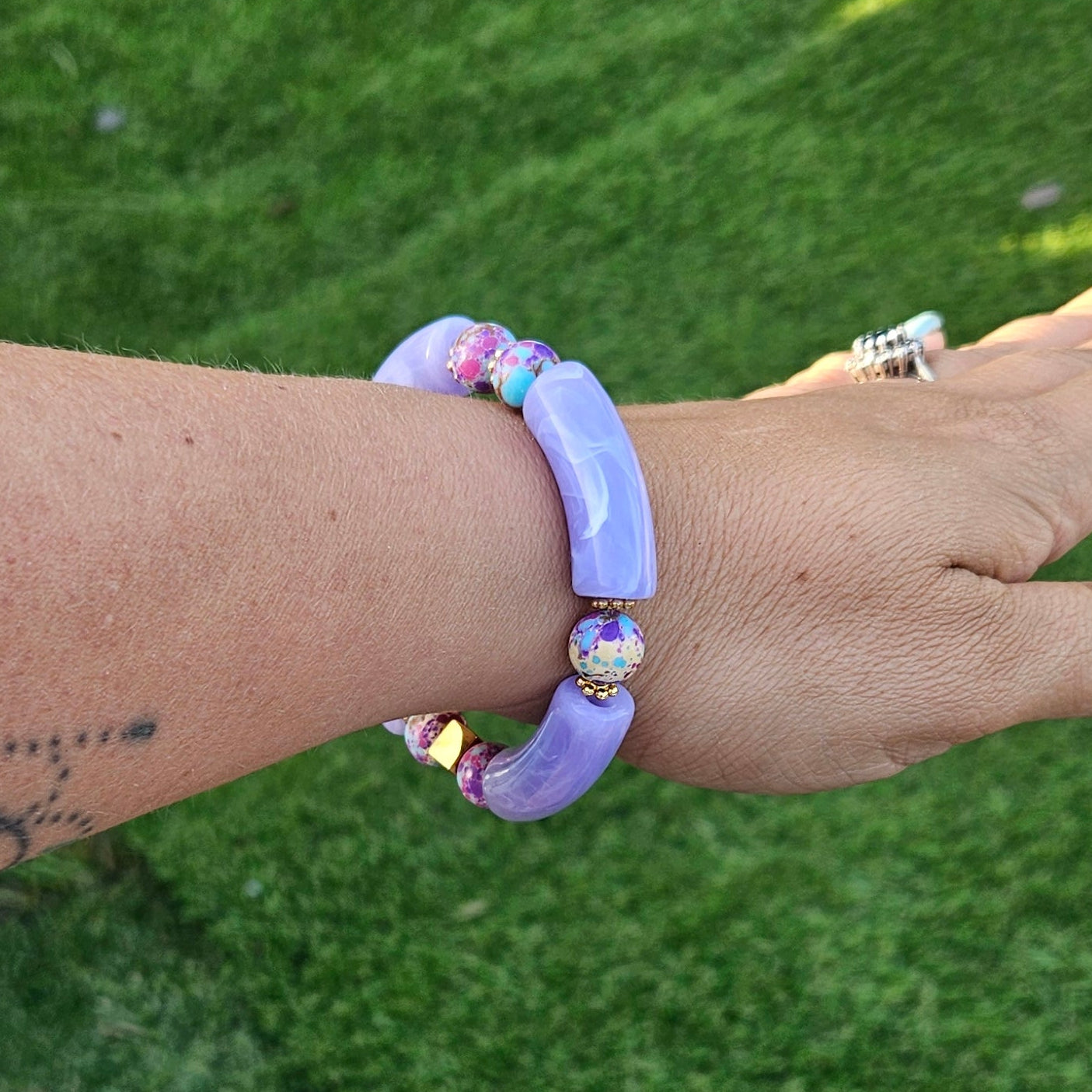 Woman wearing the Galaxy Skies Bracelet stacked with other Fleur & Stone bracelets in natural outdoor light.
