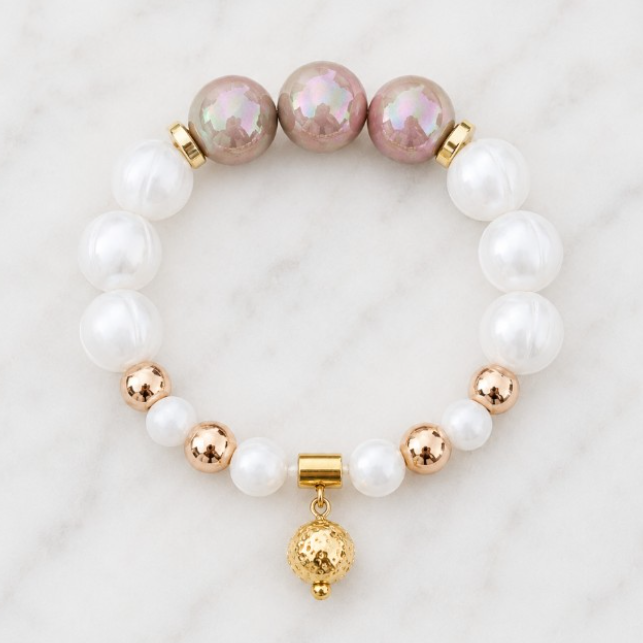 Handmade Morning Dew bracelet featuring white silicone beads, pearlescent ivory accent beads, polished gold Hematite beads and a gold pendant on a white marble background.