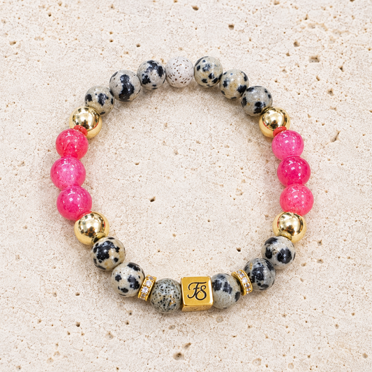 Pink Horizon natural Dalmatian Jasper and Rhodochrosite gemstone bracelet with gold hematite beads and Fleur & Stone logo.