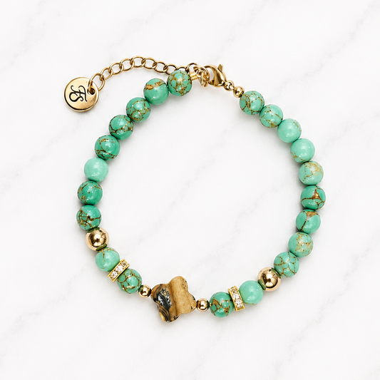 Handmade Ocean Clover bracelet featuring natural Green Turquoise gemstone beads, a Picture Jasper clover centrepiece, gold Hematite accents and gold stainless steel clasp on a white marble background.