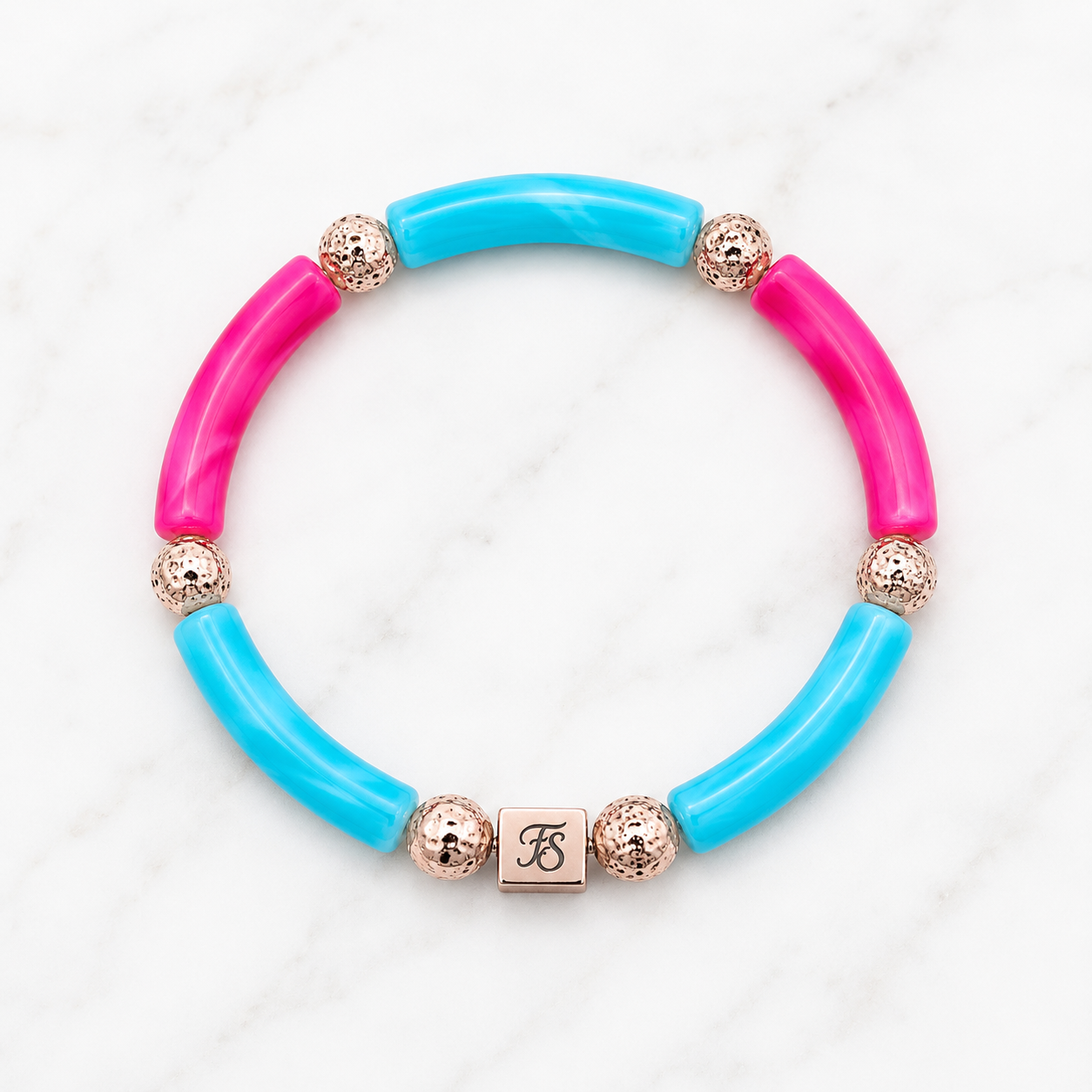 Pink Lagoon Bracelet by Fleur & Stone featuring turquoise and pink acrylic tube beads, textured rose gold lava beads and a rose gold stainless steel logo bead on a white marble background.