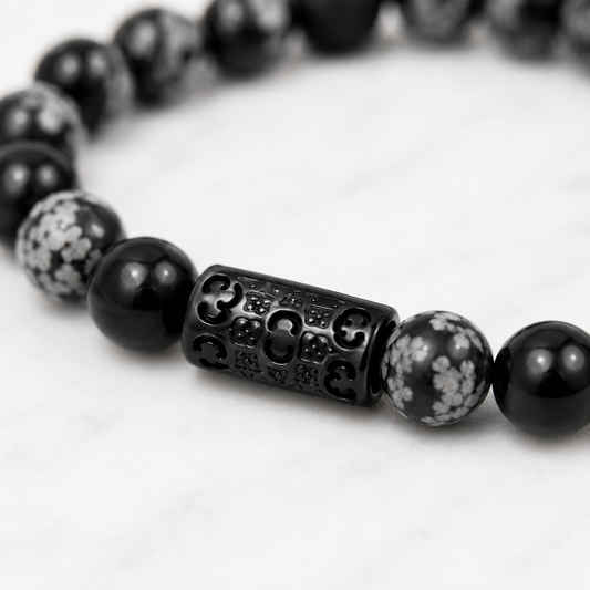 Close-up of the black stainless steel Fleur & Stone signature connector on a Snowflake Obsidian bracelet.