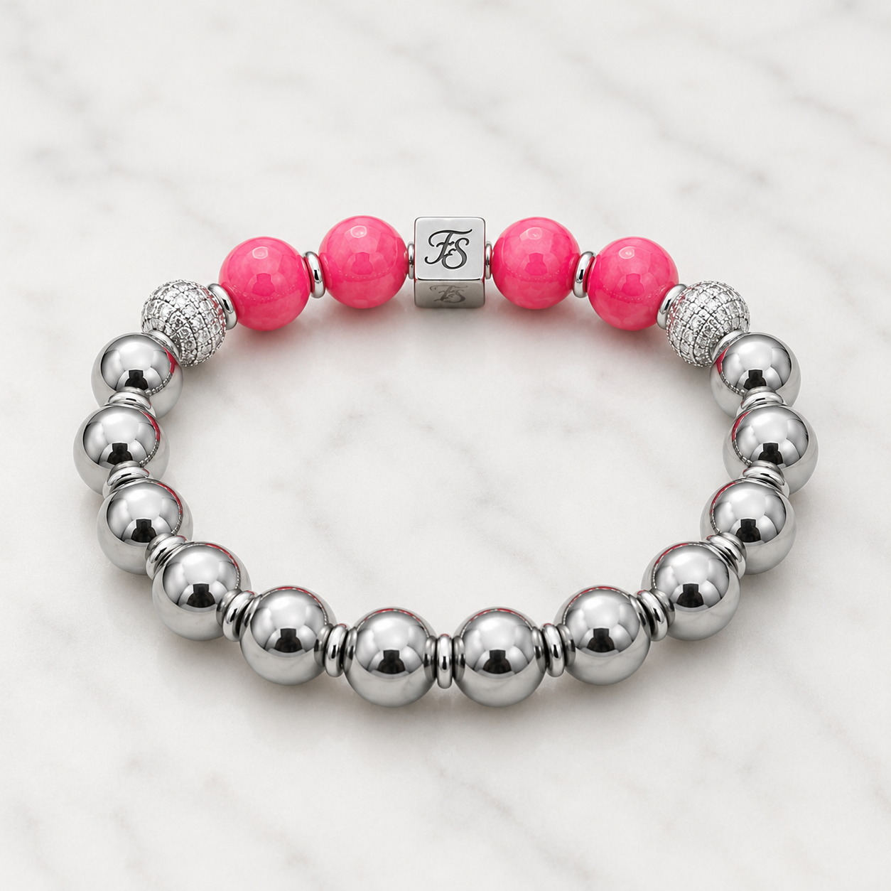 Natural Rhodochrosite and Silver Hematite gemstone bracelet with 10mm beads, silver rhinestone spacers and stainless steel Fleur & Stone logo bead on a light white marble background.