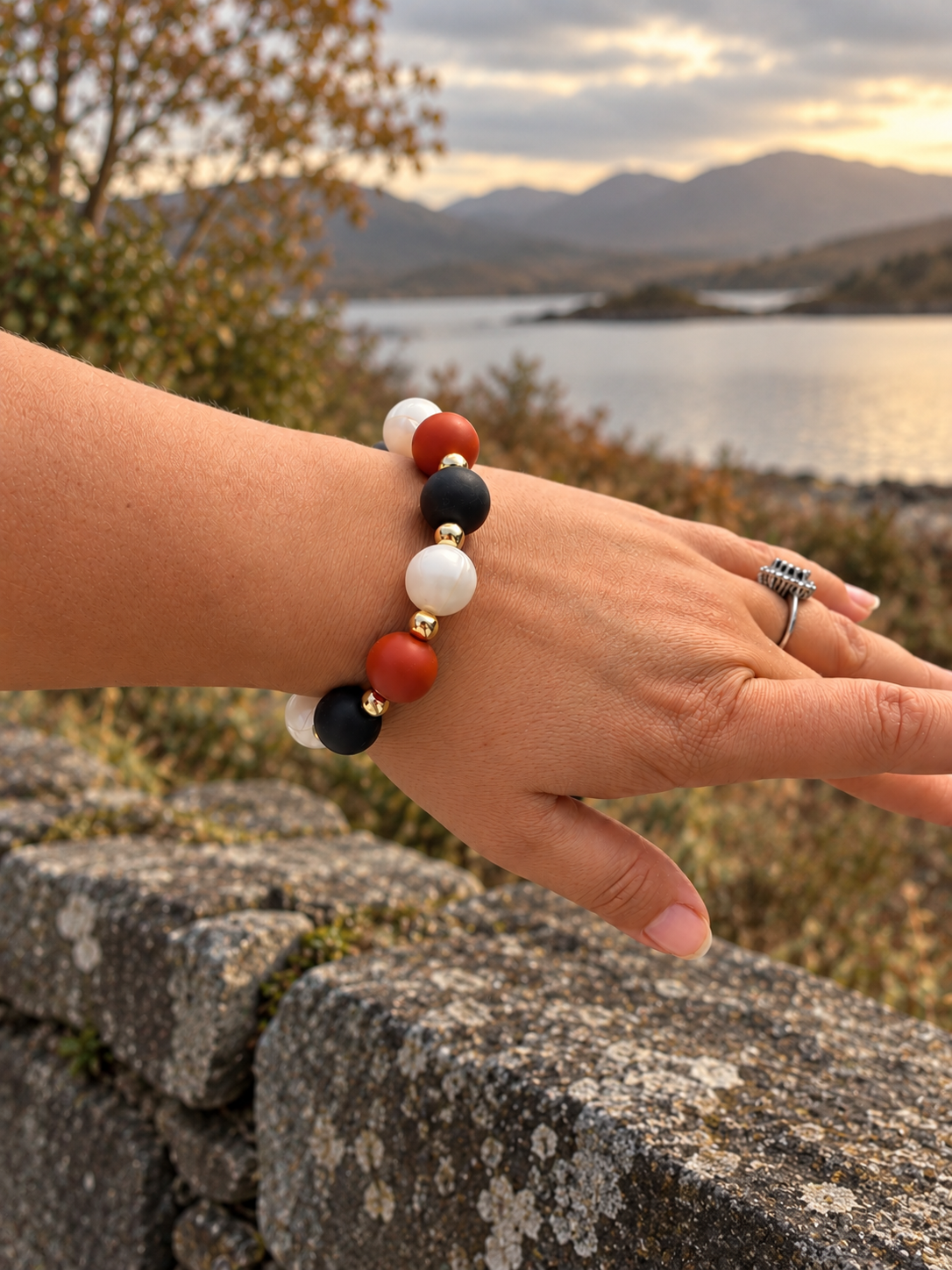 Ember Moon silicone bead bracelet worn on wrist with black terracotta pearly white beads and gold hematite accents